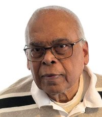 Elderly man wearing glasses and striped sweater.