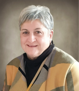 Smiling person with short gray hair and colorful sweater.