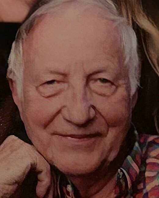 Smiling older man in multicolored shirt.