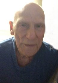 Older man in blue shirt indoors.