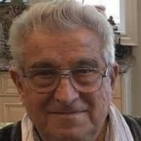 Elderly man wearing glasses indoors smiling.