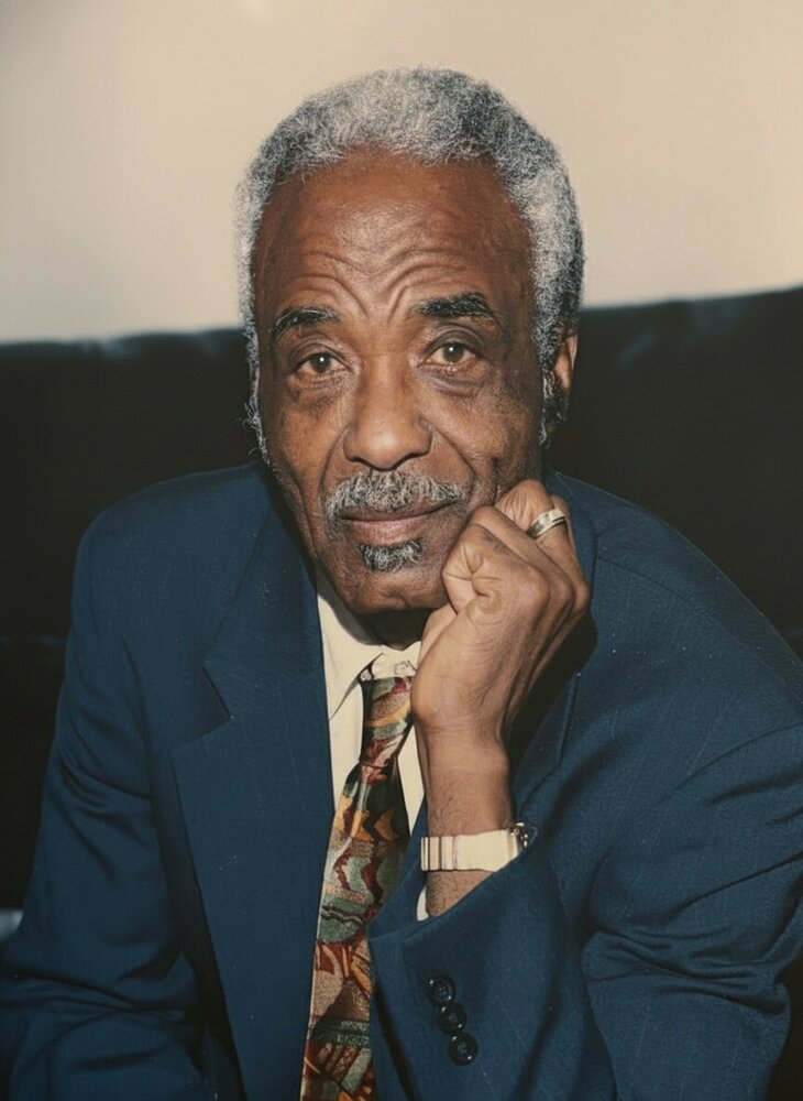 Elderly man in blue suit, thoughtful expression.