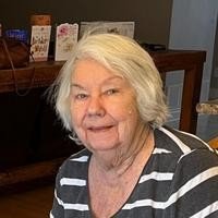 Smiling older woman in striped shirt indoors.