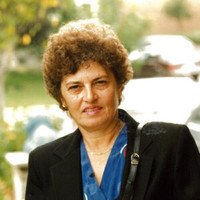 Person outdoors wearing a blue shirt and black jacket.