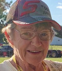 Elderly woman outdoors wearing a cap and glasses.