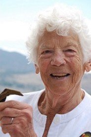 Smiling elderly woman holding a chocolate triangle.