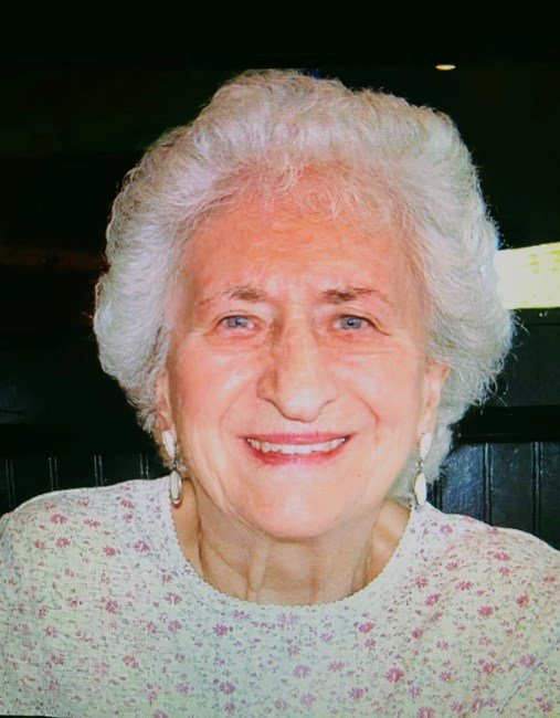 Smiling elderly woman with silver hair in sweater.