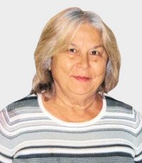 Elderly woman smiling, wearing striped shirt.