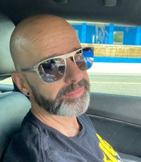 Bald man with sunglasses driving a car