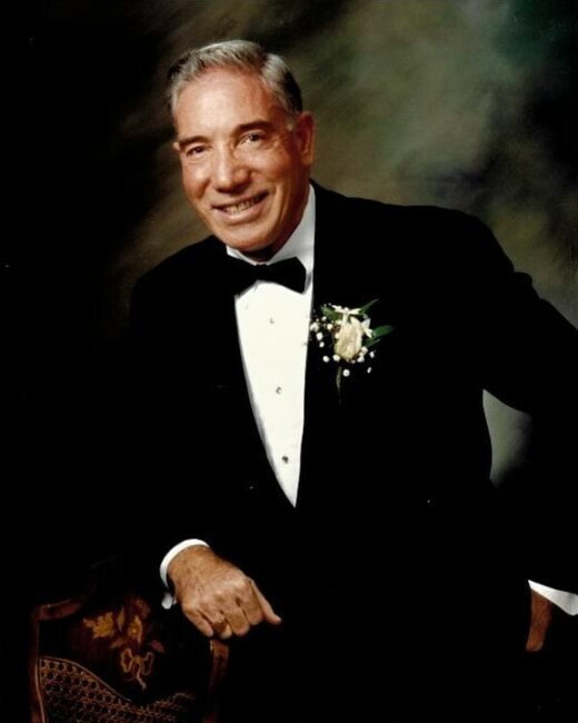 Smiling elderly man in tuxedo, boutonniere on lapel.