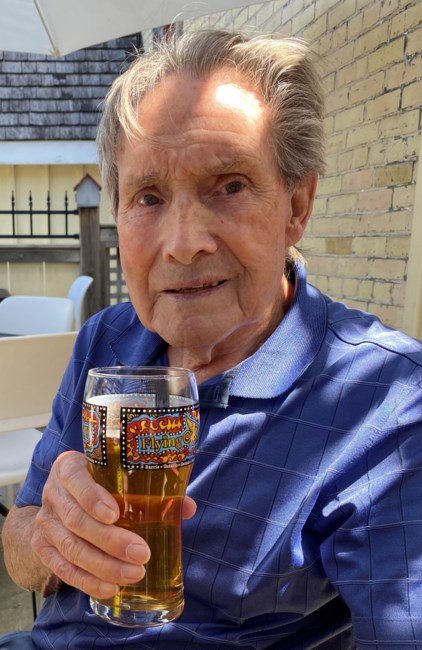 Elderly man enjoying a beer outdoors.