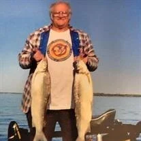 Man holding two large fish on a boat.