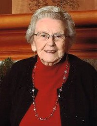 Smiling older woman in glasses and red sweater.
