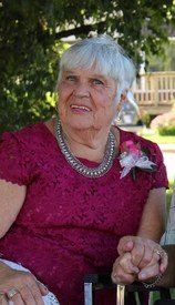 Elderly woman in red dress, sitting outside.