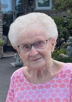 Elderly woman smiling outside a house.