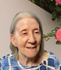 Smiling elderly woman with flowers in background.