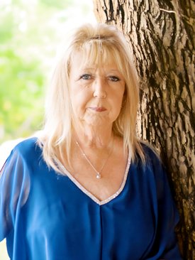 Woman in blue shirt leaning against tree