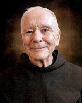 Elderly man in a brown robe smiling