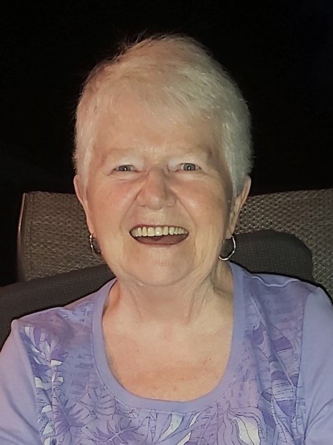 Smiling elderly woman in purple shirt.