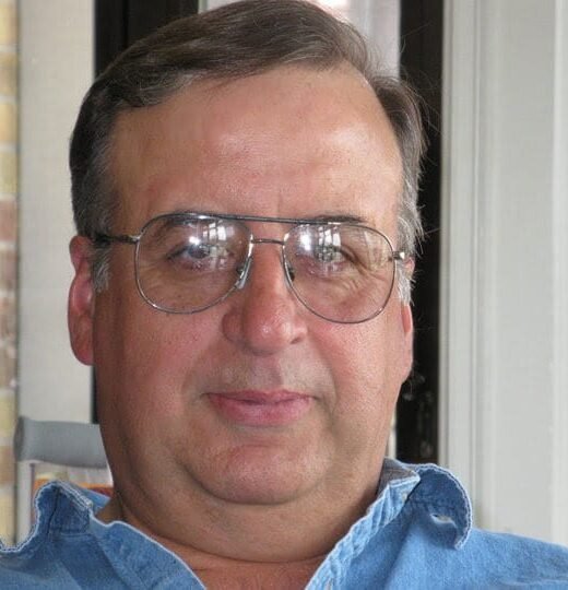 Middle-aged man wearing glasses and denim shirt.