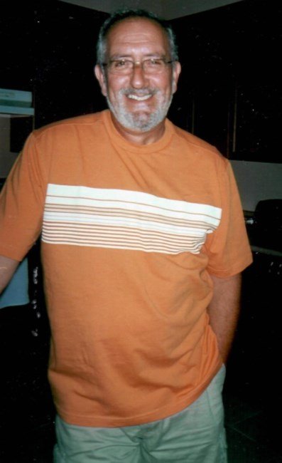 Smiling man in orange shirt indoors.