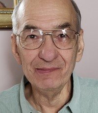 Elderly man wearing glasses and a light shirt.