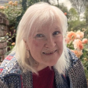 Smiling person with flowers in background.