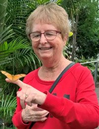 Smiling woman in red holding a butterfly.