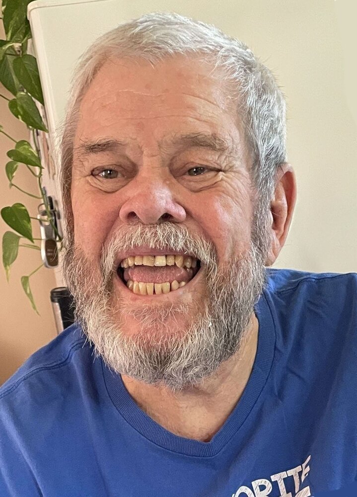 Elderly man smiling, wearing blue shirt.