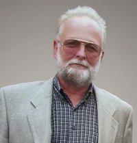 Man in sunglasses and blazer, neutral background.