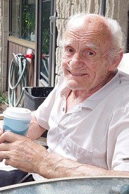 Elderly man smiling and holding a coffee cup.