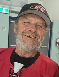 Smiling man wearing a red hockey jersey and cap.