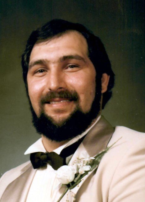 Smiling man with beard in suit and bow tie.