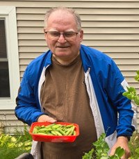 Man holding a tray of fresh vegetables outside.