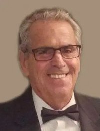 Smiling man wearing glasses and a bow tie.