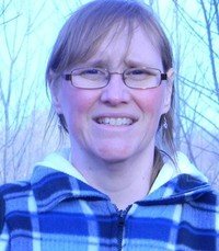Person outdoors in blue plaid jacket smiling.