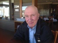 Elderly man sitting indoors near a window.