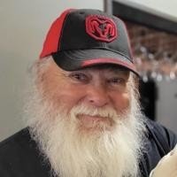 Bearded man wearing a red and black cap.