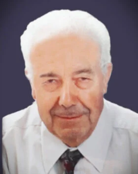 Elderly man in white shirt smiling slightly.