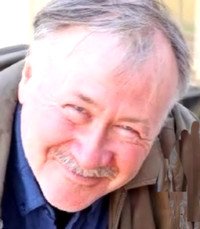 Smiling older man outdoors wearing jacket.