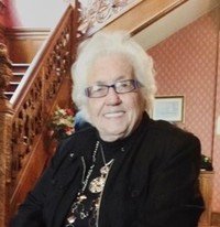 Elderly woman smiling indoors by staircase