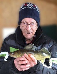 Elderly person holding a fish, wearing a winter hat.