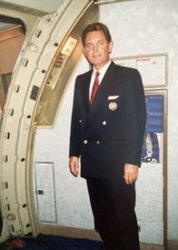 Airline pilot standing in aircraft doorway.