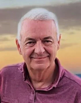 Smiling man at sunset backdrop.