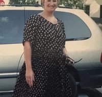Person in polka dot dress standing by a car.