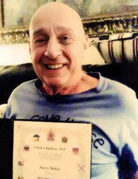 Smiling man holding a framed document on couch.