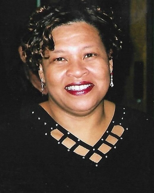 Smiling woman with short curly hair and earrings.