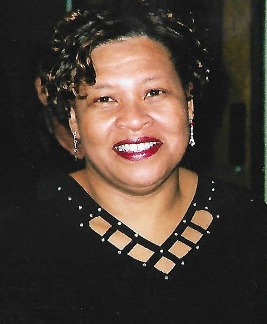 Smiling woman with short curly hair and earrings.
