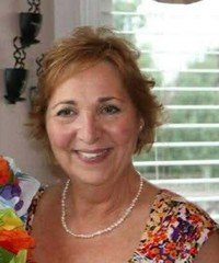 Smiling woman indoors, holding a colorful bouquet.