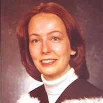 Portrait of a smiling woman in formal attire.